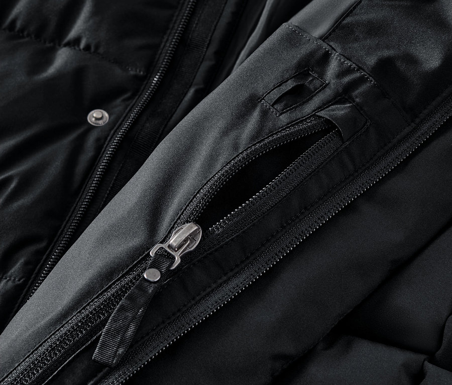 Detail černého kabátu s rozepnutým zipem na kapse.