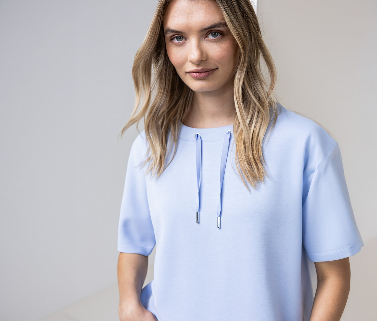 Žena má na sobě světle modré triko Street One se šňůrkami u výstřihu.