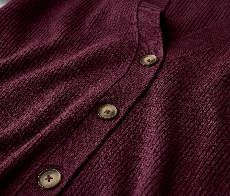 Detail bordového svetru se třemi hnědými knoflíky.