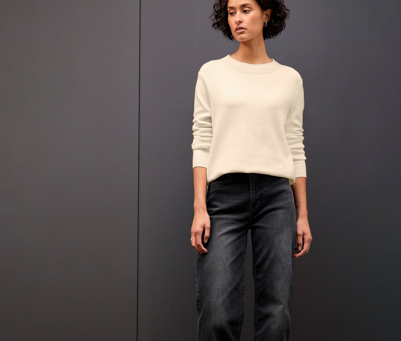 Žena má na sobě béžový pletený svetr s rolovaným lemem Street One.