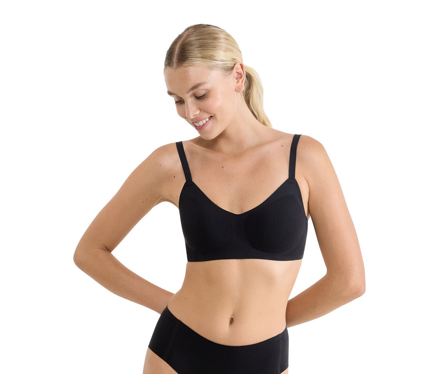 Usměvavá žena v černé žebrované měkké podprsence sloggi ZERO Feel Pure Soft bra a ladících černých kalhotkách.