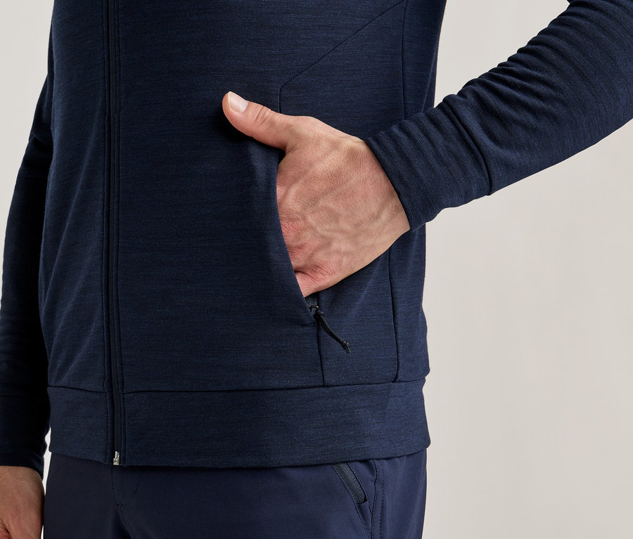Detail osoby v tmavě modré bundě na zip s rukou v kapse.