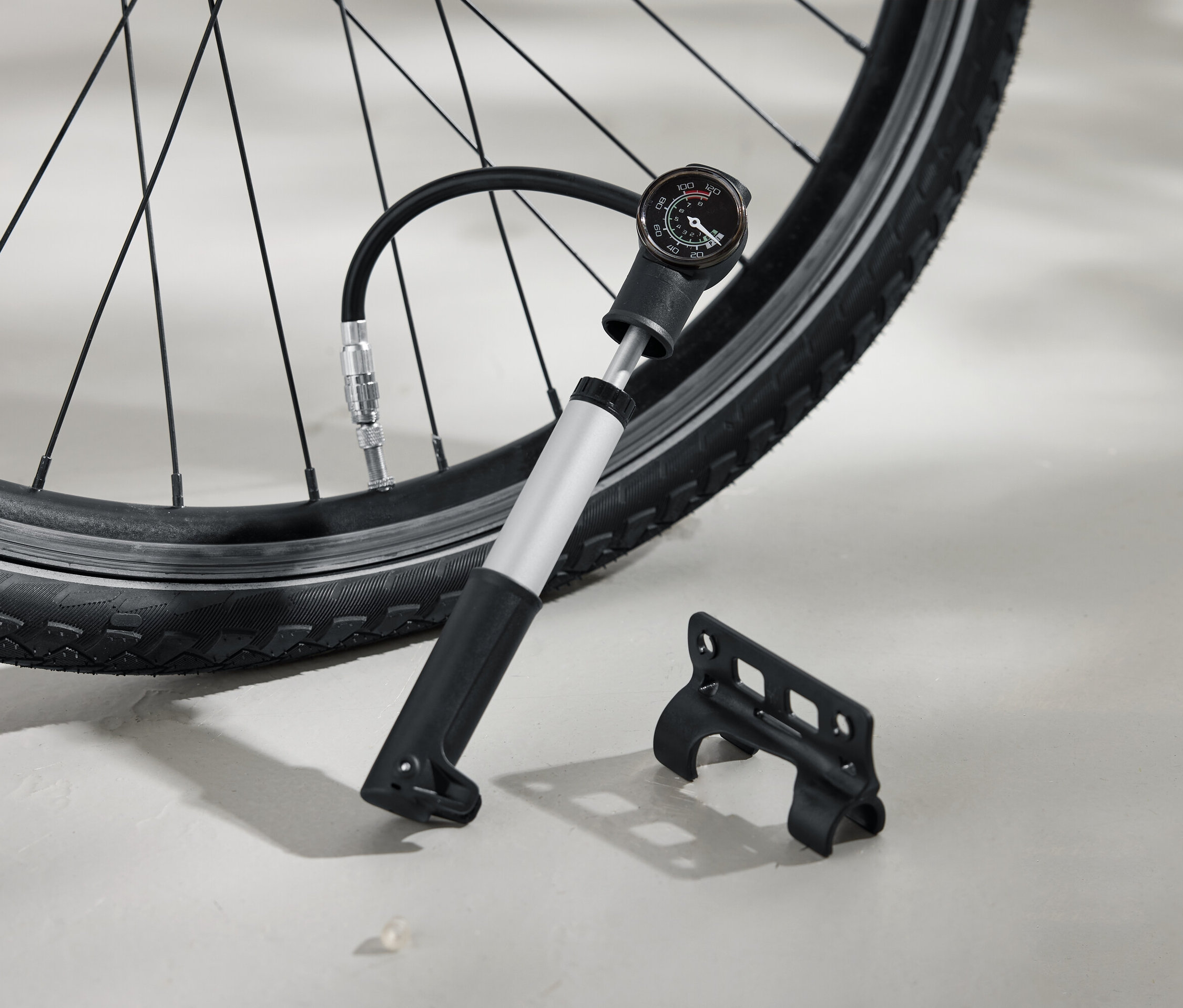 Pneumatika kola je nahuštěna stříbrnou pumpou s černou rukojetí a analogovým manometrem. Vedle na zemi leží černý držák.