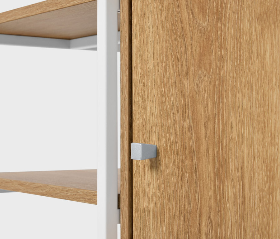 Detailní pohled na regál s dřevěnými policemi a dřevěnými dveřmi se čtvercovou stříbrnou rukojetí.