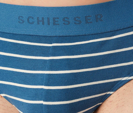 Muž má na sobě modro-bílé pruhované slipy SCHIESSER Rio. Modrý pas má logo SCHIESSER.