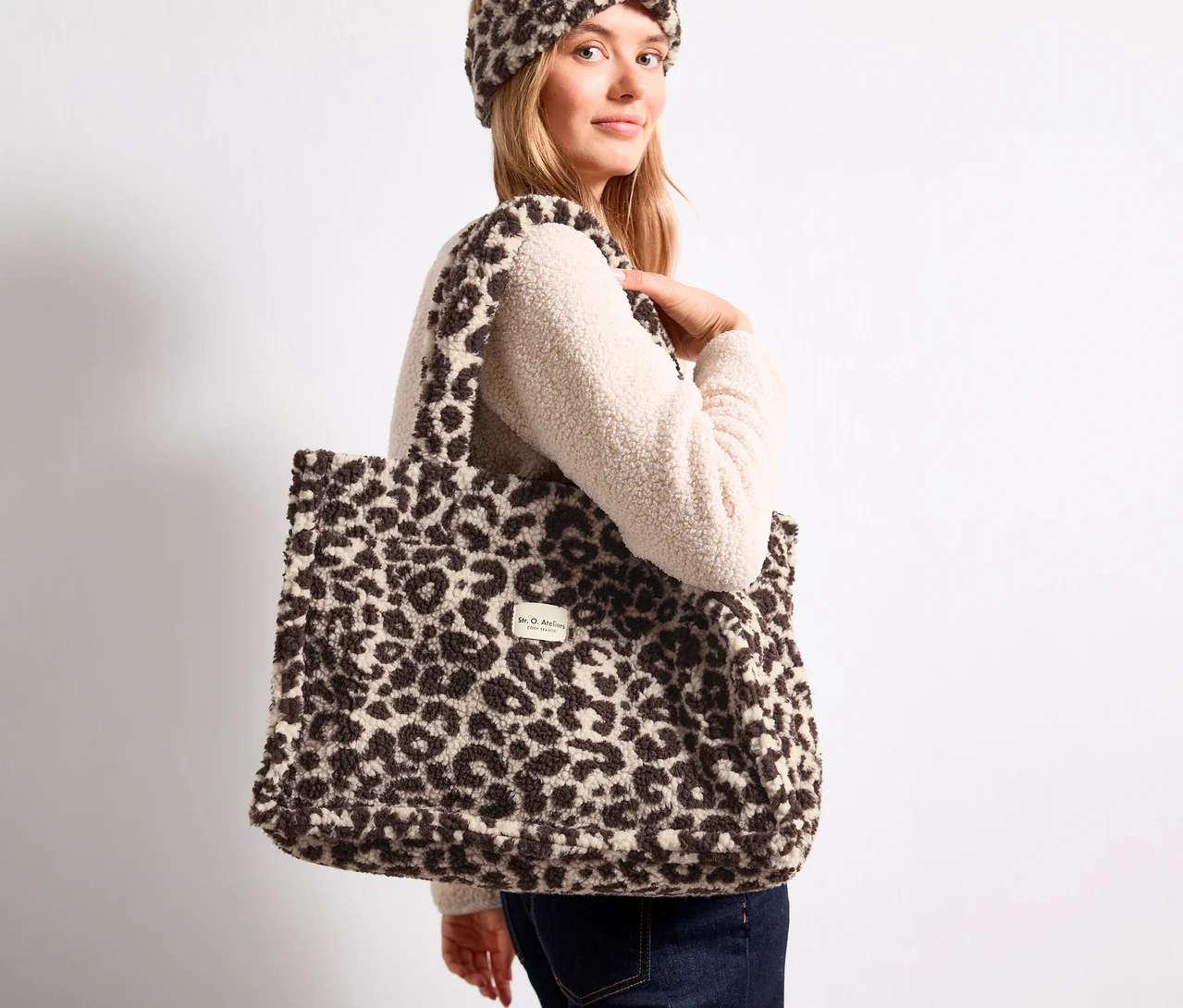 Blondýnka nese na rameni chlupatou nákupní tašku Street One s leopardím vzorem a má na sobě sladěnou čelenku.