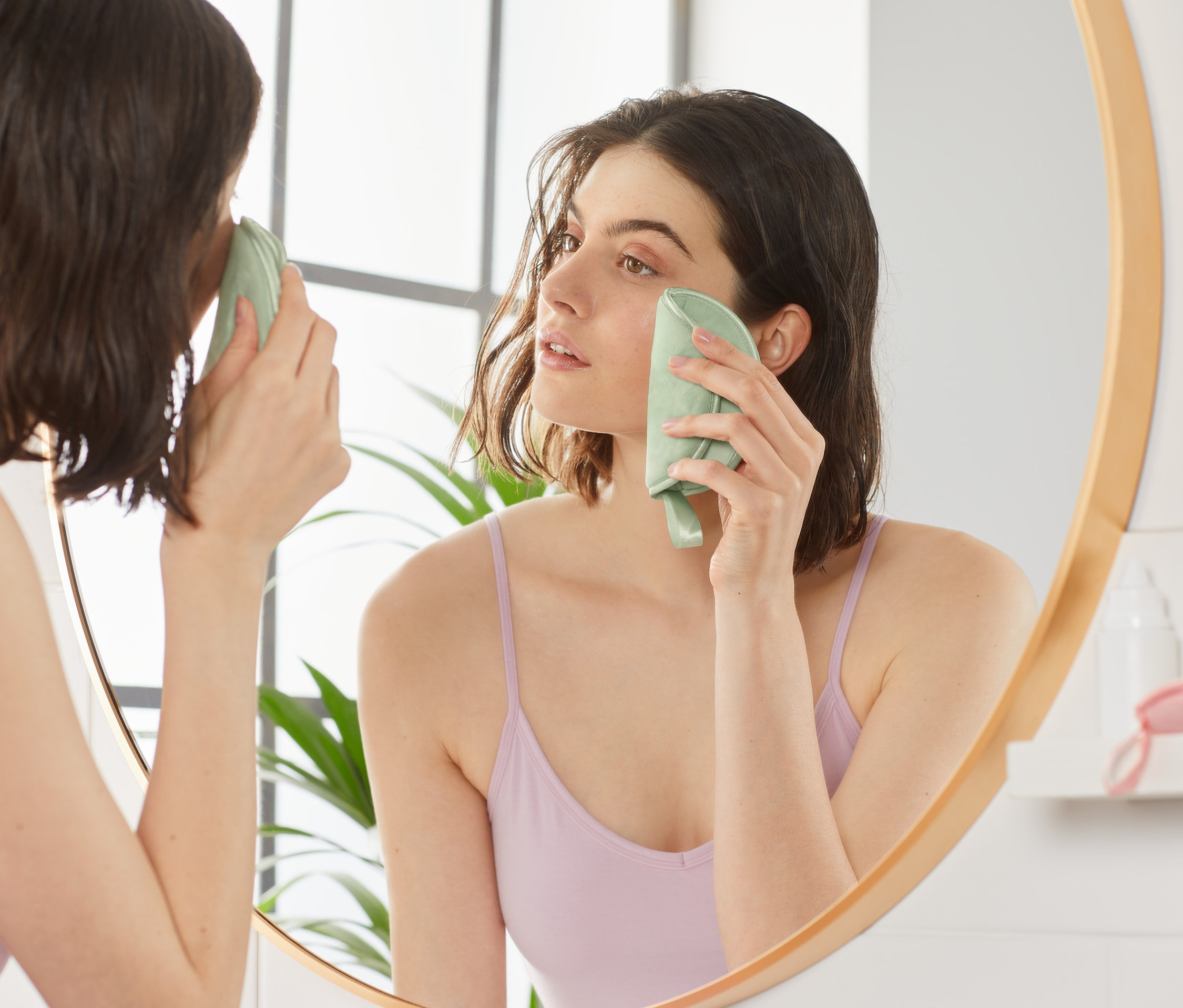 Žena si odličuje make-up z obličeje pomocí extra velkého opakovaně použitelného odličovacího tampónu, 3 ks, a dívá se do zrcadla.