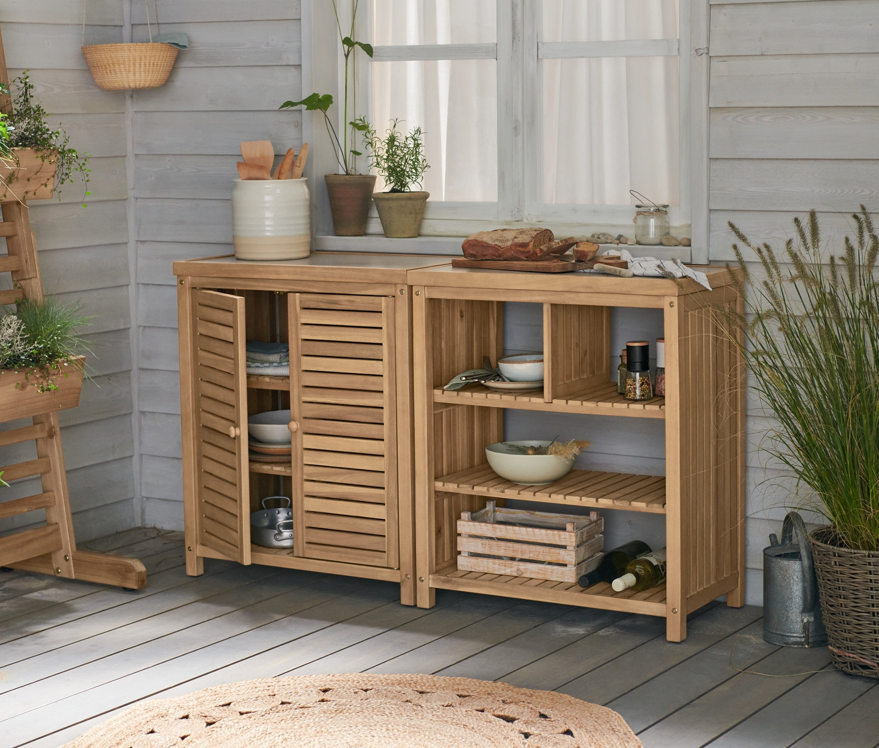 Dvě zahradní skříně »Frieso« s betonovou pracovní deskou stojí vedle sebe. Vlevo je vertikální záhon »Tinus« s truhlíky.