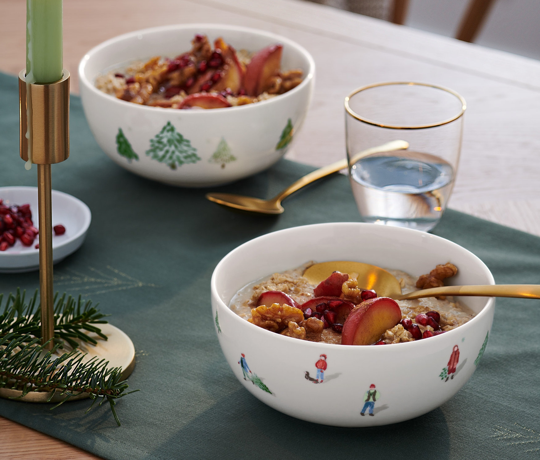 Dvě misky na müsli s ovocem na stole s vánoční dekorací.