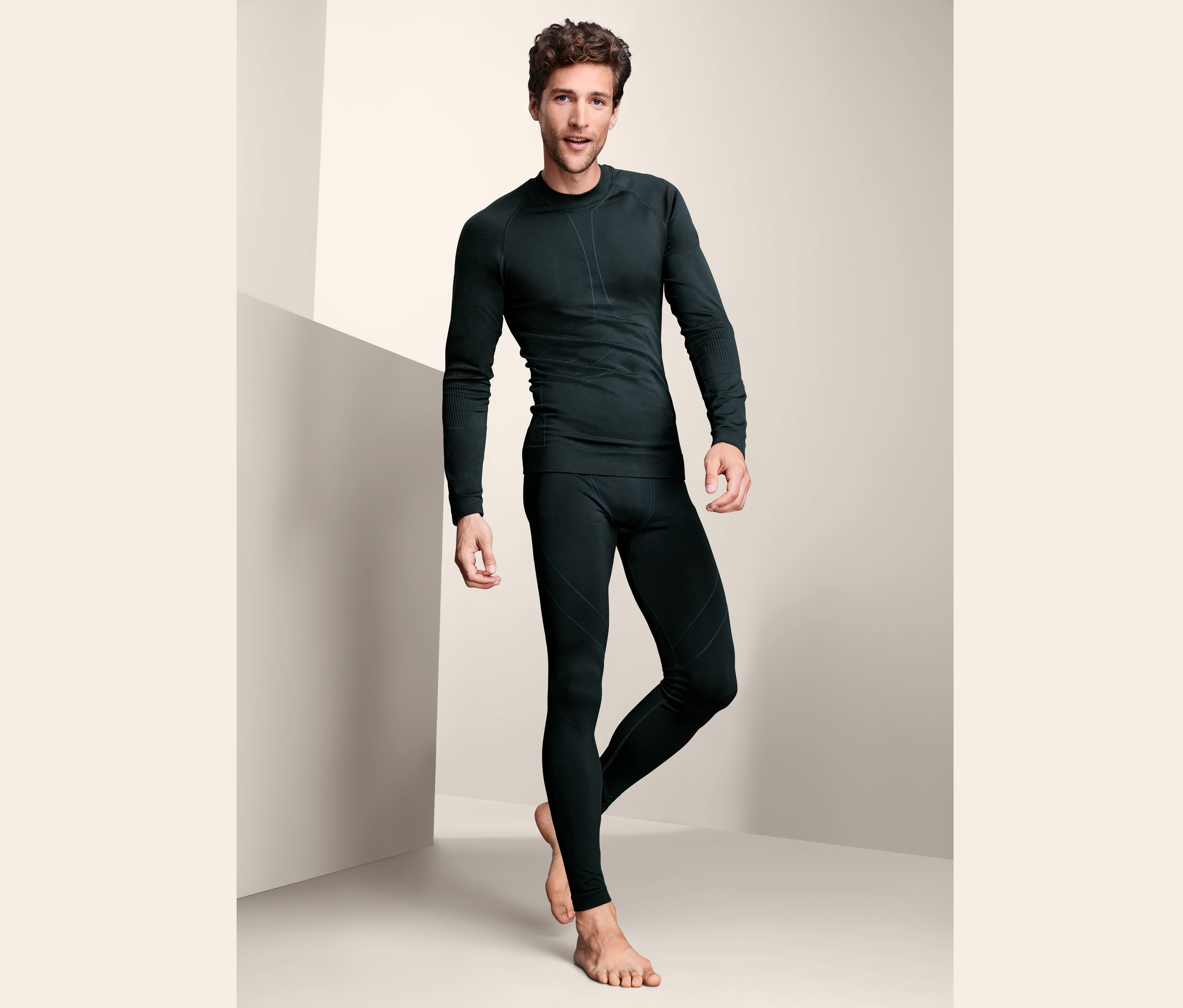 Muž pózuje v černém bezešvém funkčním spodním prádle.