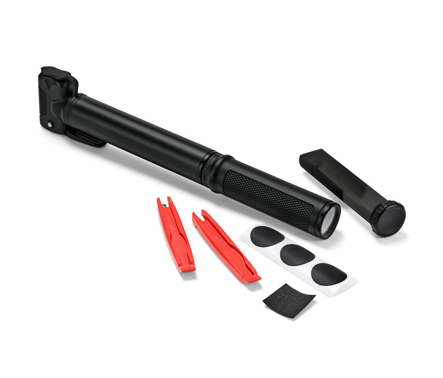 Černá pumpička na kolo leží vedle dvou červených montážních pák, záplat a smirkového papíru.