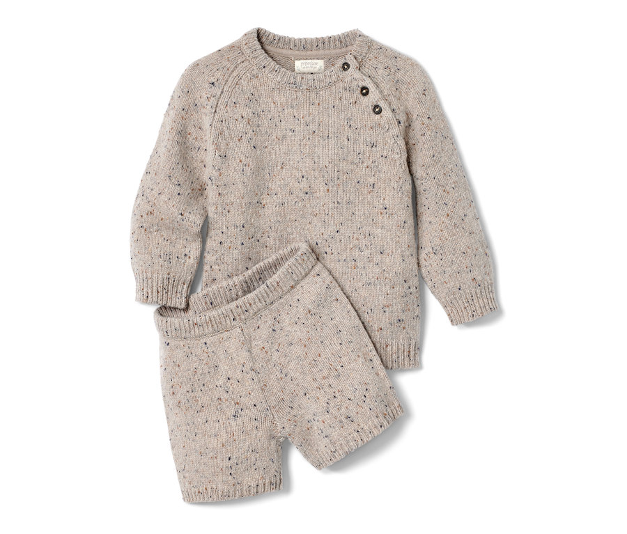 Pletená souprava s merino vlnou leží na bílém pozadí.