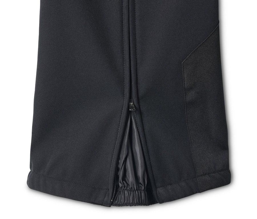 Detail černé lyžařské kalhoty se zipem u kotníku.