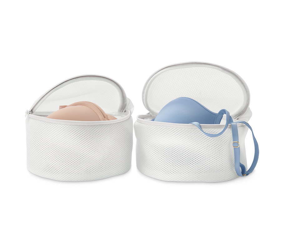 Dvě bílé síťky na praní podprsenek, v každé je jedna podprsenka.