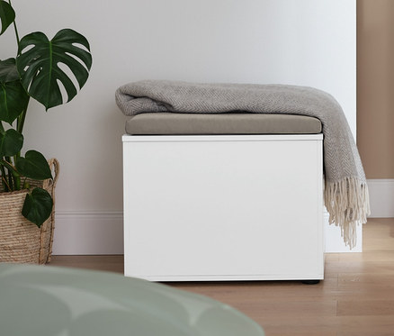 V pokoji stojí němý sluha a úložný prostor s možností sezení, na kterém leží deka.