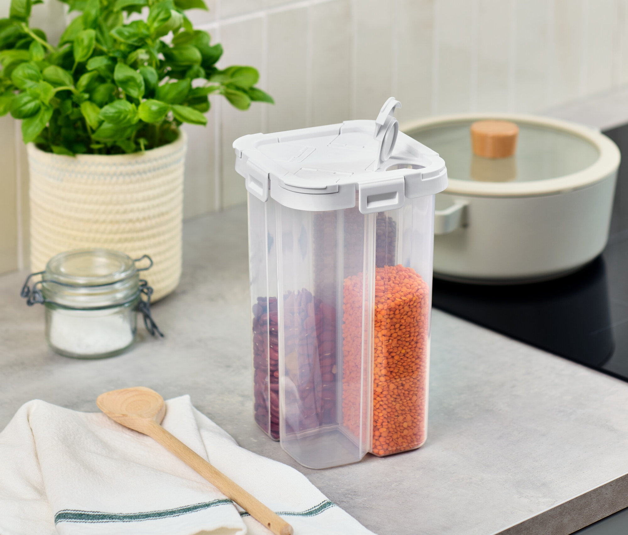 Na lince stojí dóza na potraviny 4 v 1, vedle ní je bazalka v květináči a sklenice s víkem.