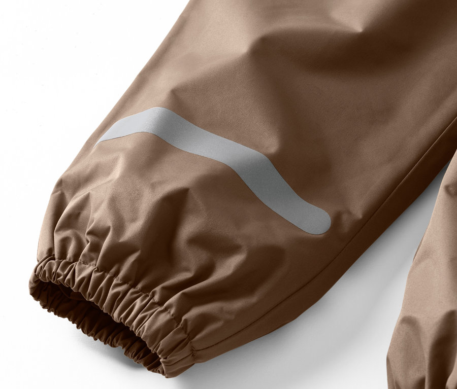 Detail dětských kalhot do deště s reflexním pruhem na nohavici.