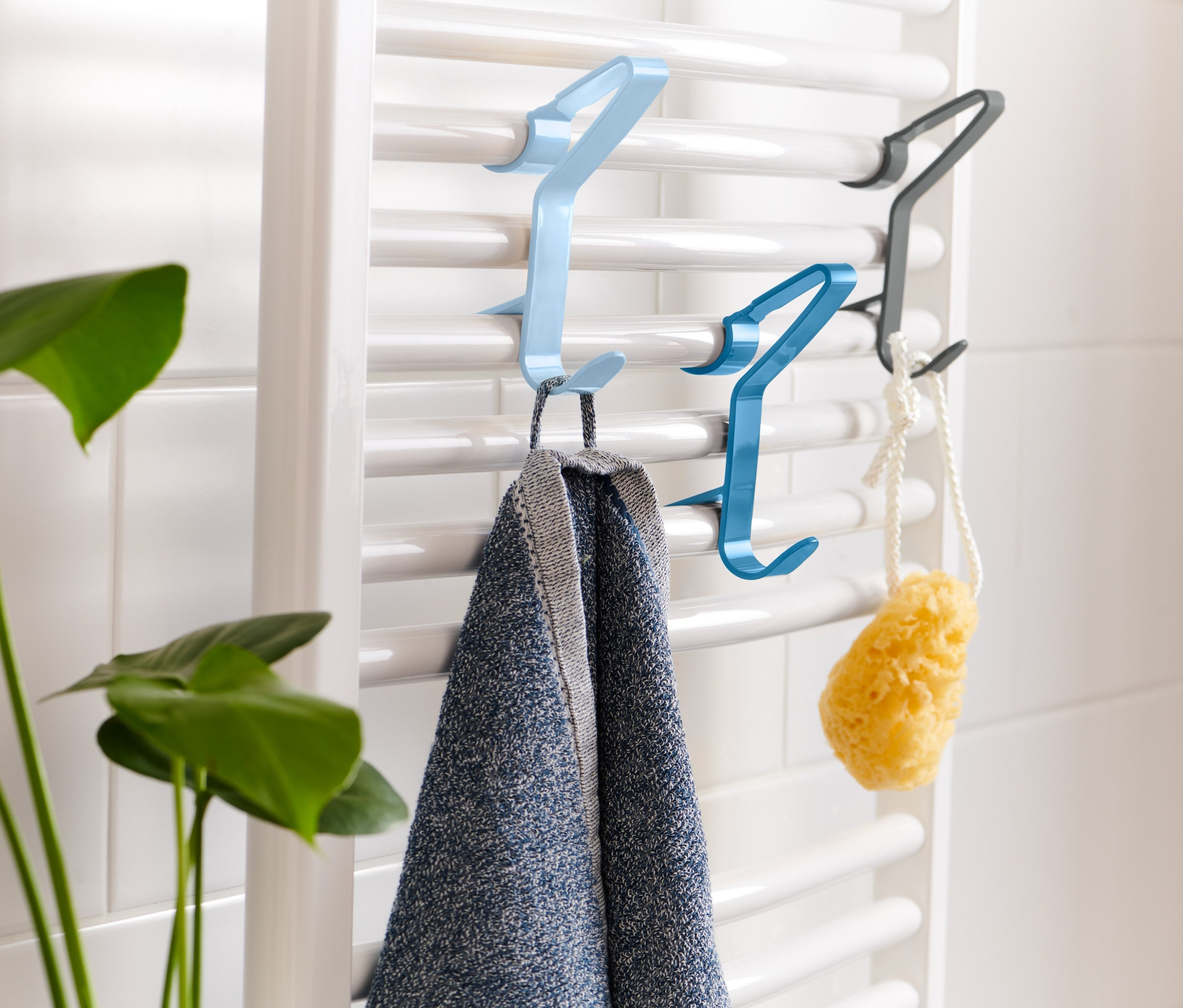Na topení jsou zavěšeny 3 háčky: světle modrý, modrý a černý. Na světle modrém háčku visí ručník, na modrém houba.