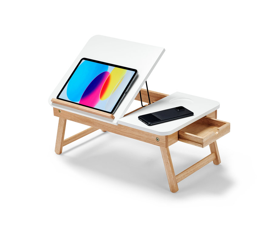 Bílý stolek na notebook do postele s hnědýma nohama. Na stolku je tablet a mobilní telefon.