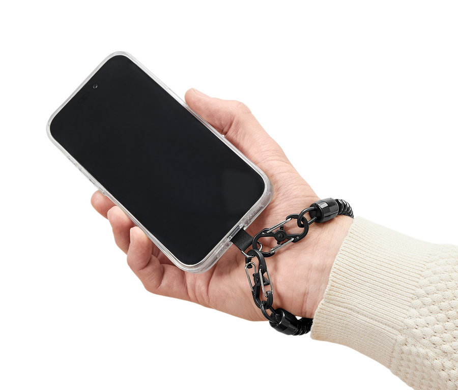 Ruka drží mobilní telefon s průhledným pouzdrem a černým bezpečnostním řetízkem.