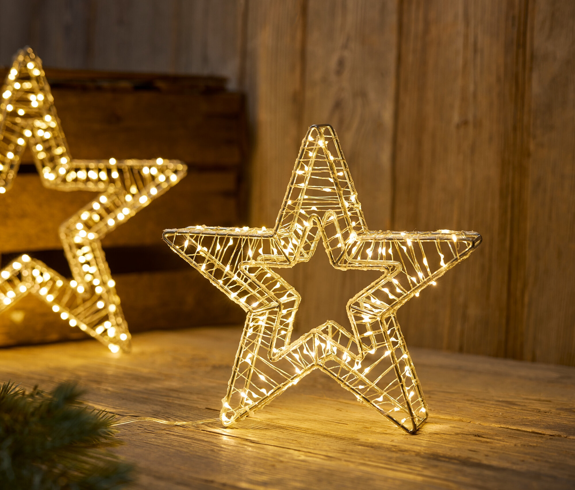 Osvětlené drátěné hvězdy na dřevěném povrchu.