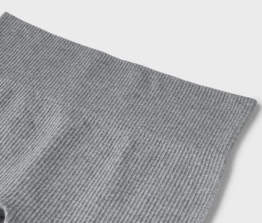 Detailní záběr šedých žebrovaných legín.