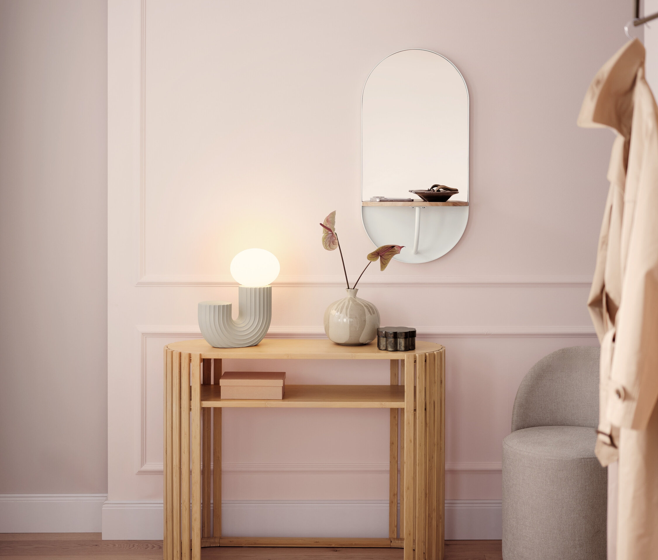 Světlá chodba s dřevěným konzolovým stolkem, lampou, zrcadlem a šedou stoličkou.