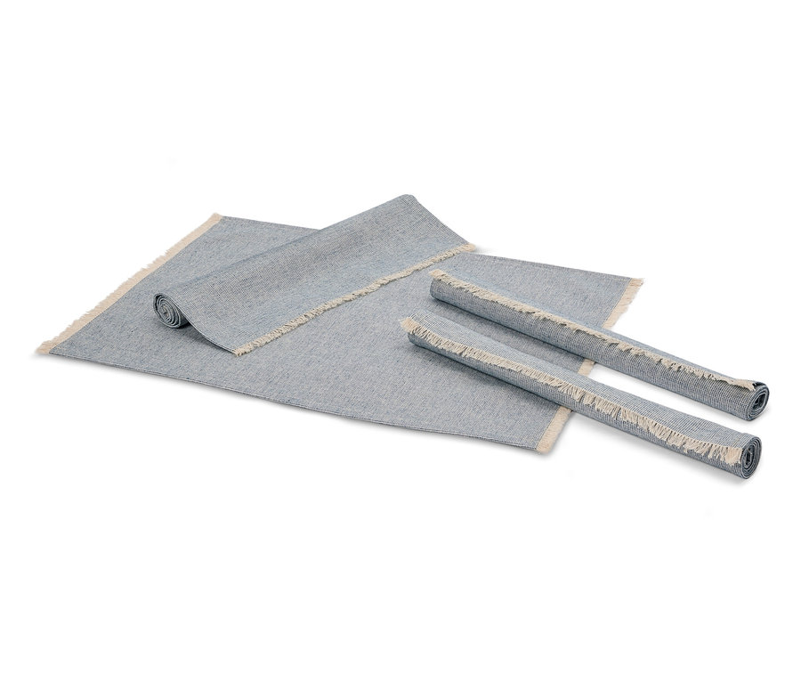Dva srolované šedé koberce a jeden rozložený šedý koberec s třásněmi.