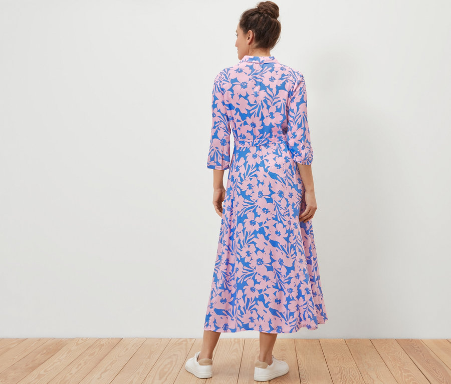 Žena zády ke kameře má na sobě košilové šaty s potiskem.