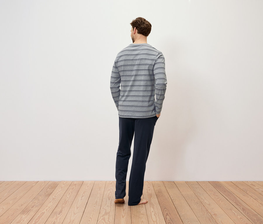 Muž zády k fotoaparátu má na sobě pruhované tričko s dlouhým rukávem a tmavě modré kalhoty.