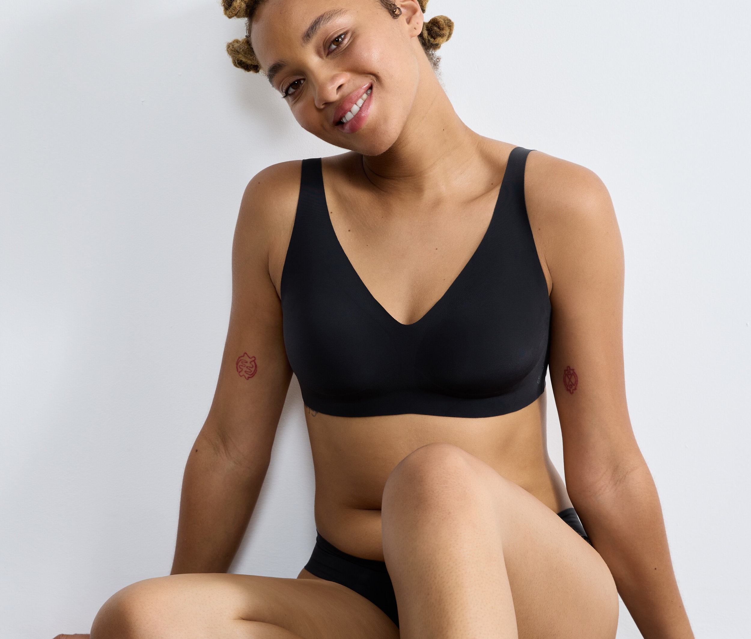 Žena sedí a má na sobě černou měkkou podprsenku sloggi ZERO Feel 2.0.