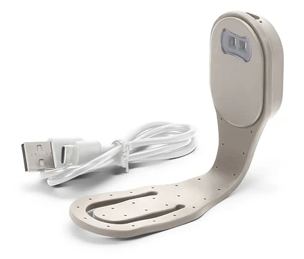 Detailní záběr béžové lampičky na čtení s bílým USB kabelem.