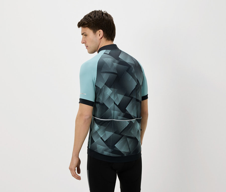 Muž zezadu v modro-černém cyklistickém dresu a černých kalhotách na bílém pozadí.