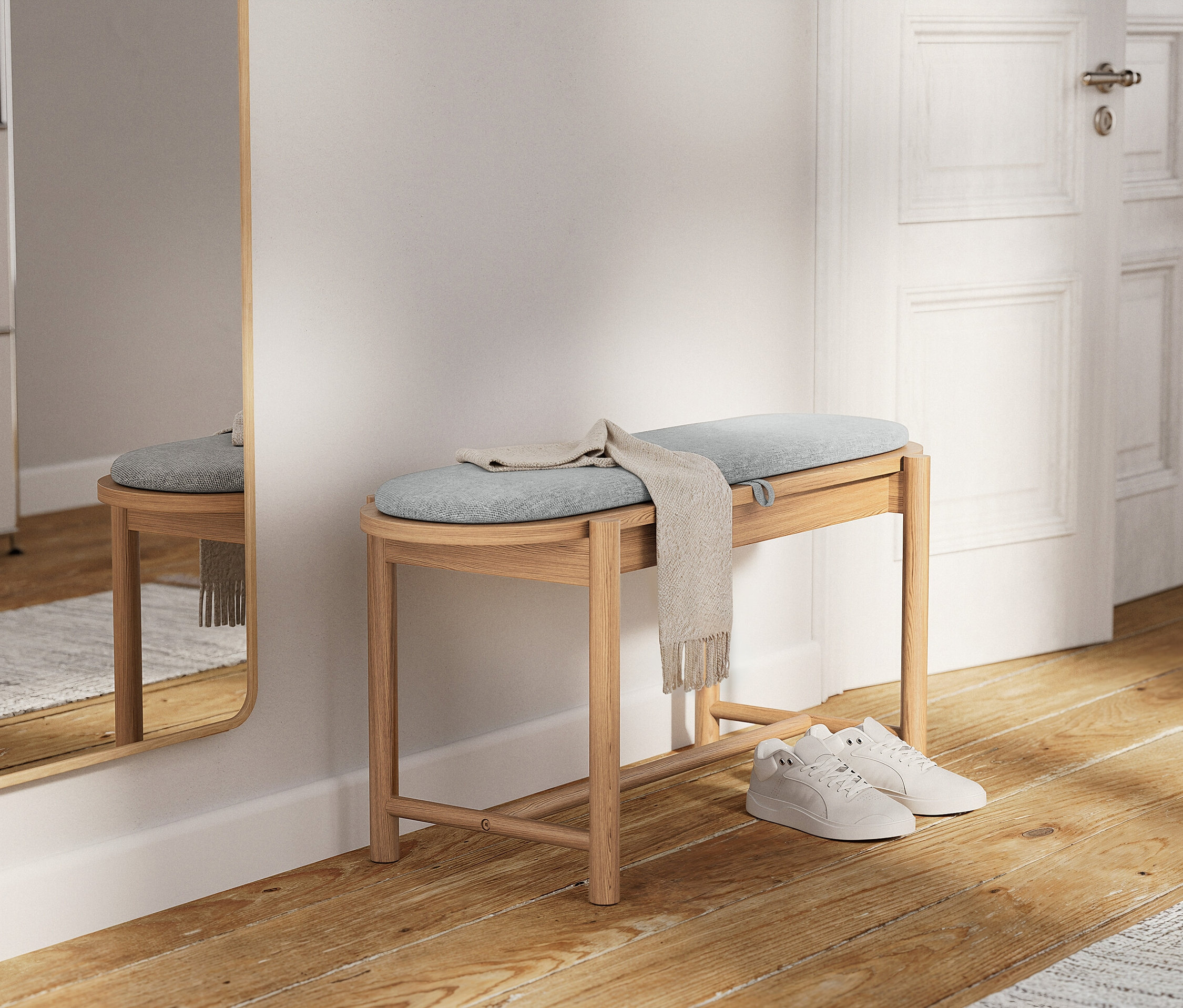 Světlá dřevěná lavice se světle modrým polštářem a béžovou šálou. Pod ním leží bílé tenisky.