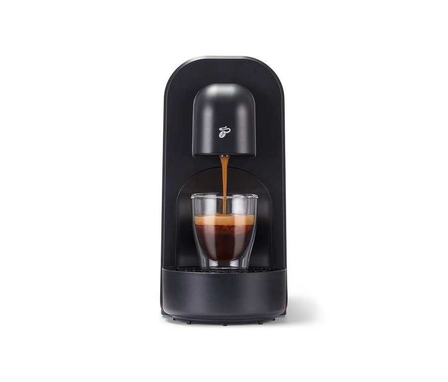 Espresso teče z černého kávovaru Cafissimo now red do sklenice.