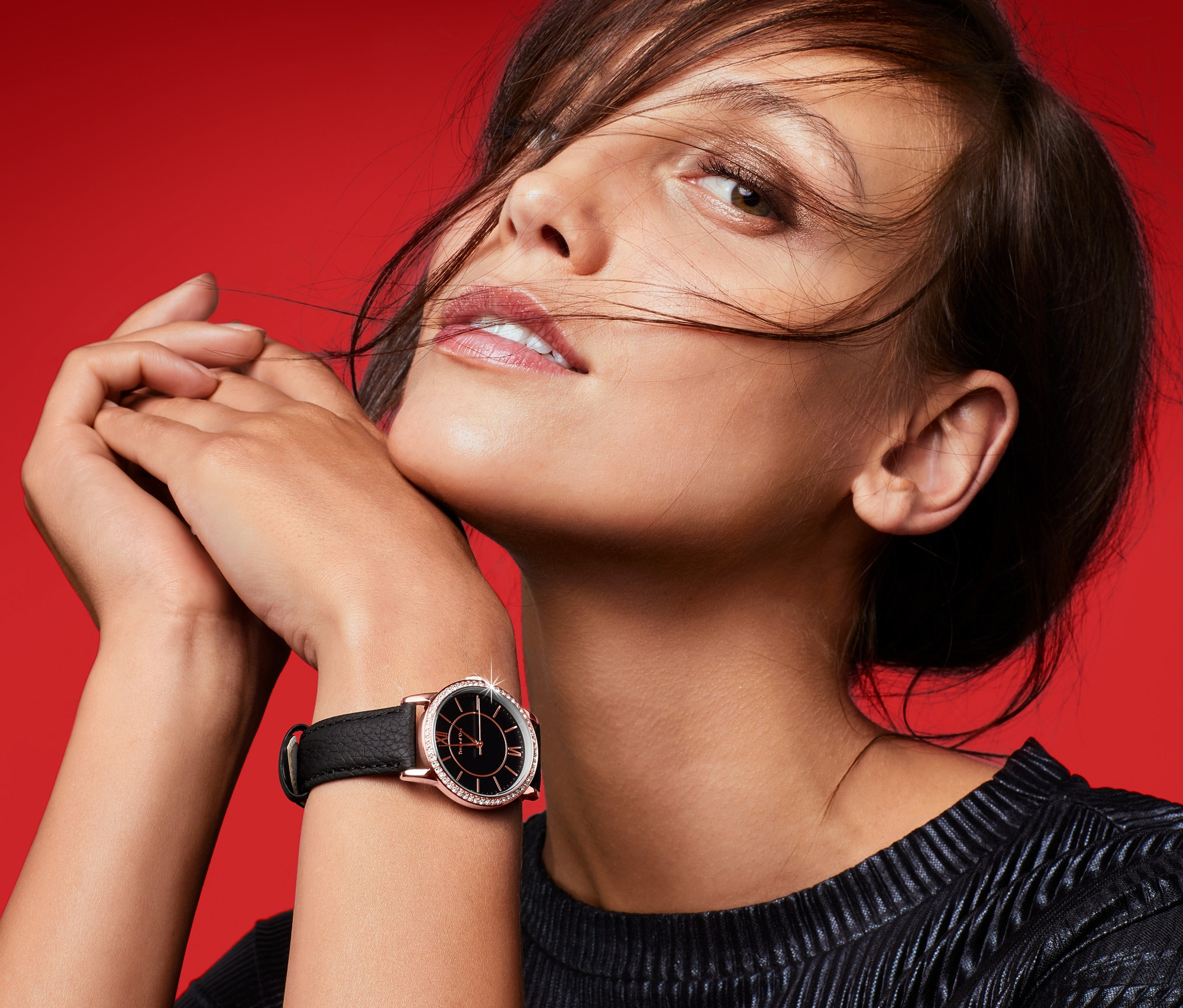 Portrét ženy s dámskými hodinkami s koženým řemínkem na červeném pozadí.
