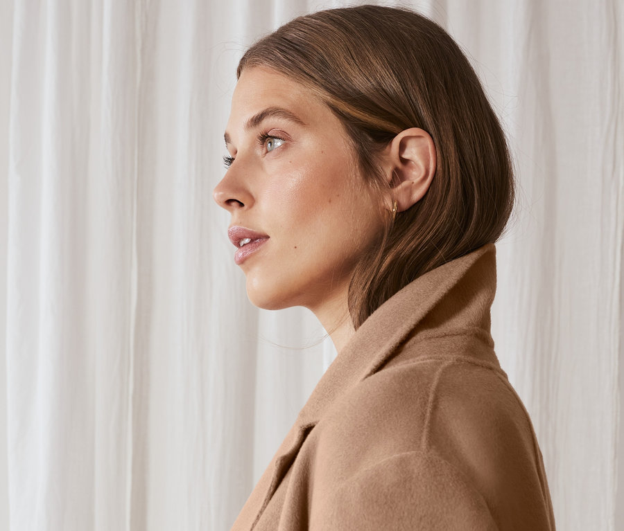 Žena z profilu má na sobě vlněný kabát s kašmírem.