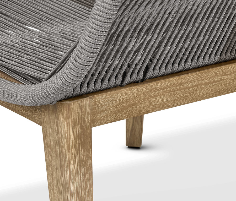 Detail designového křesla s textilním výpletem a podnožkou.