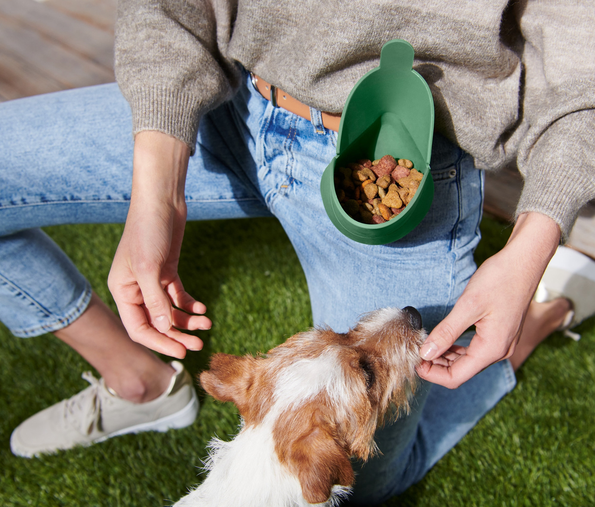 Žena dává psovi pamlsek z taštičky na pamlsky.