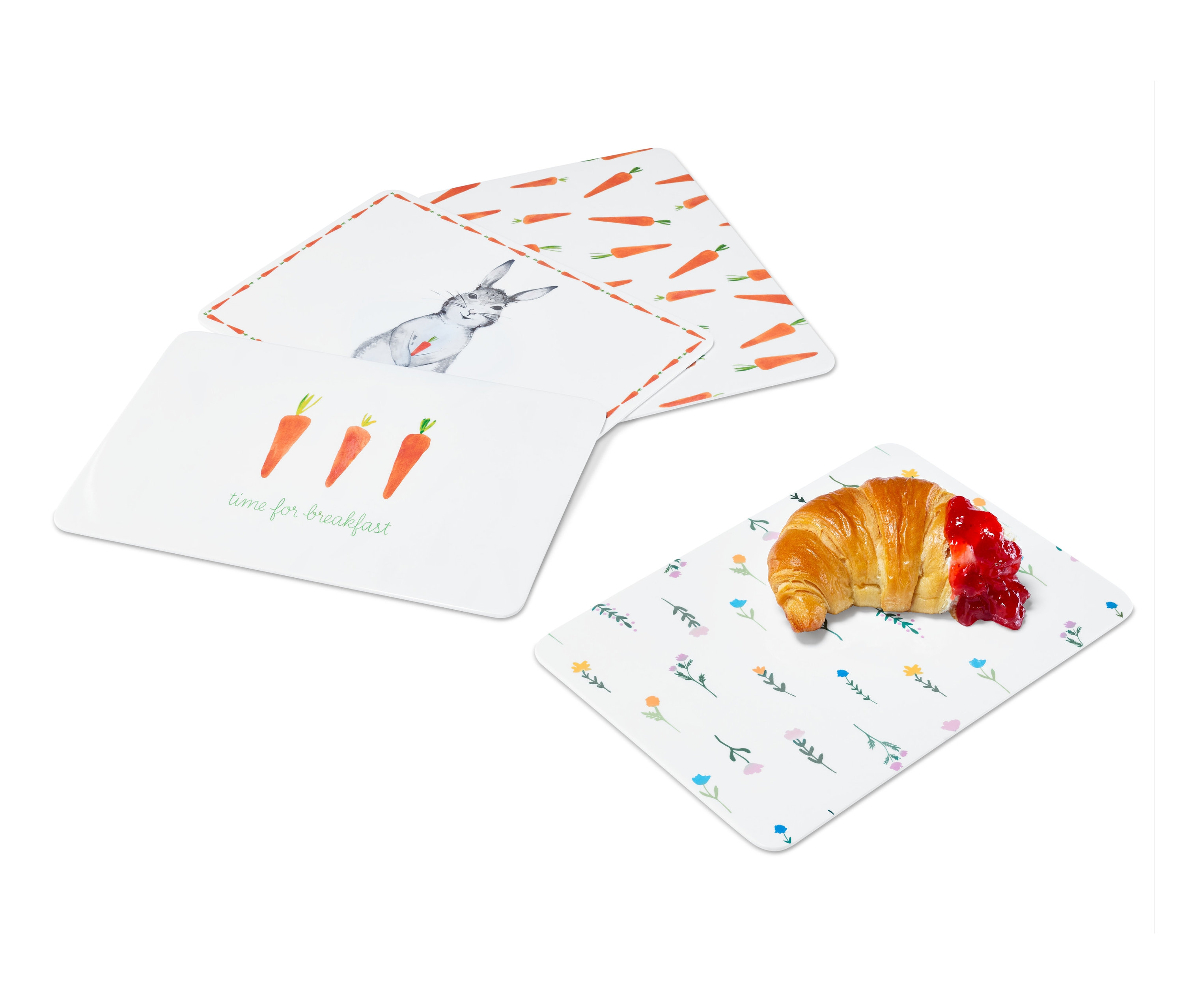 Čtyři krájecí prkénka s různými velikonočními motivy a croissant s džemem.