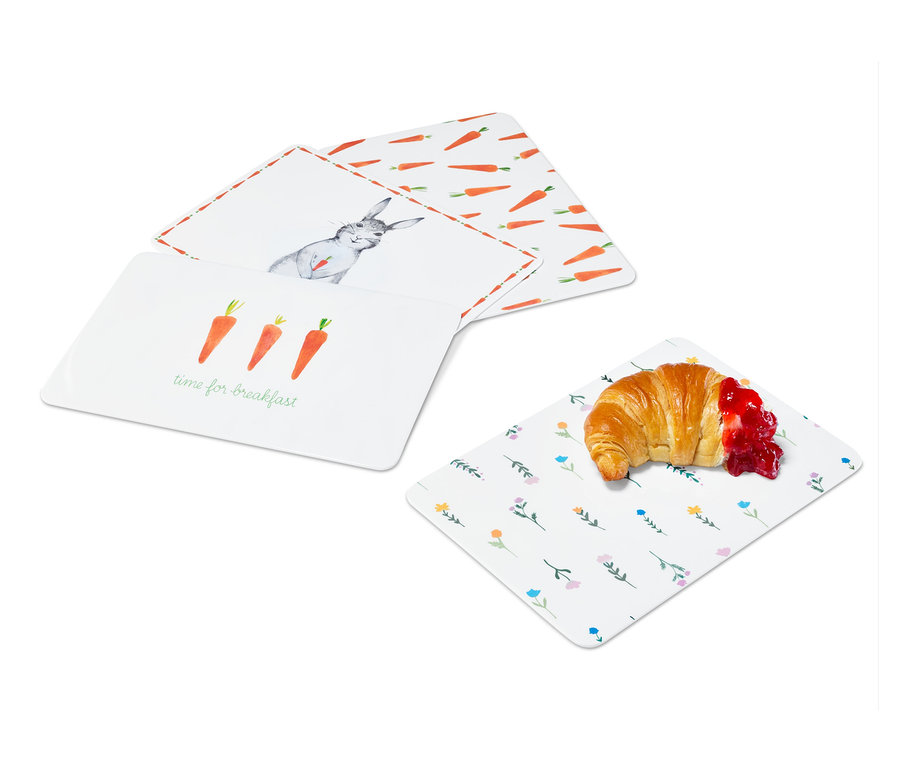 Čtyři krájecí prkénka s různými velikonočními motivy a croissant s džemem.