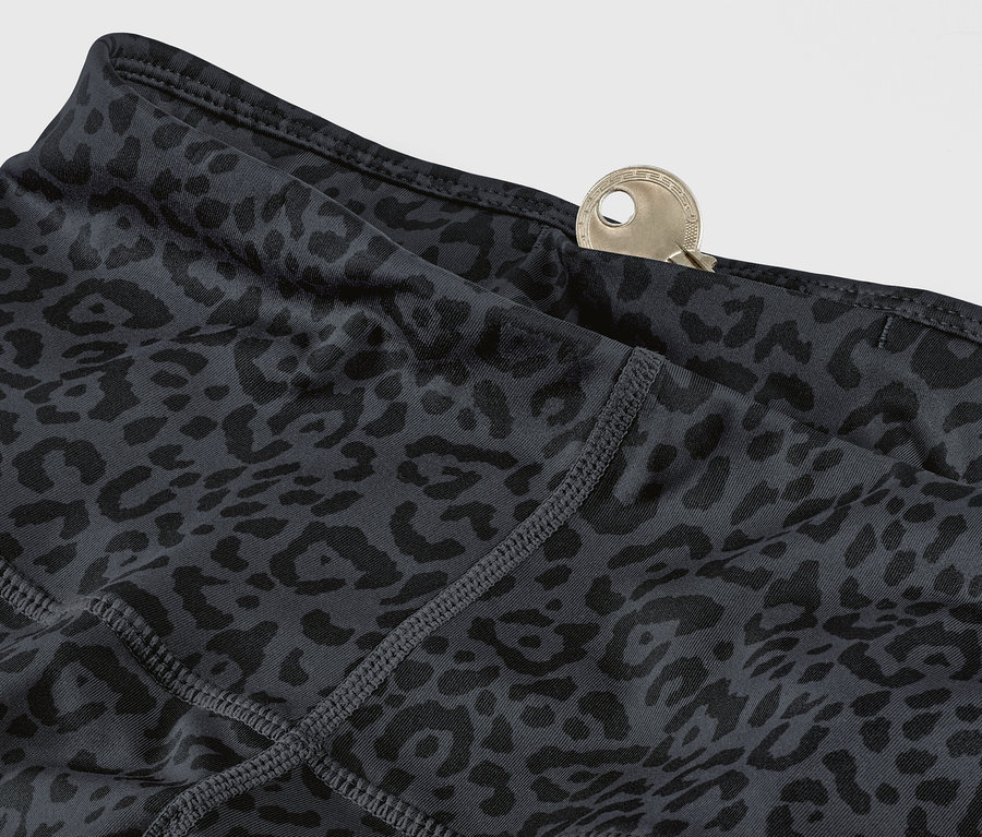 Detail šedých a černých sportovních legín s leopardím vzorem a klíčem v kapse.