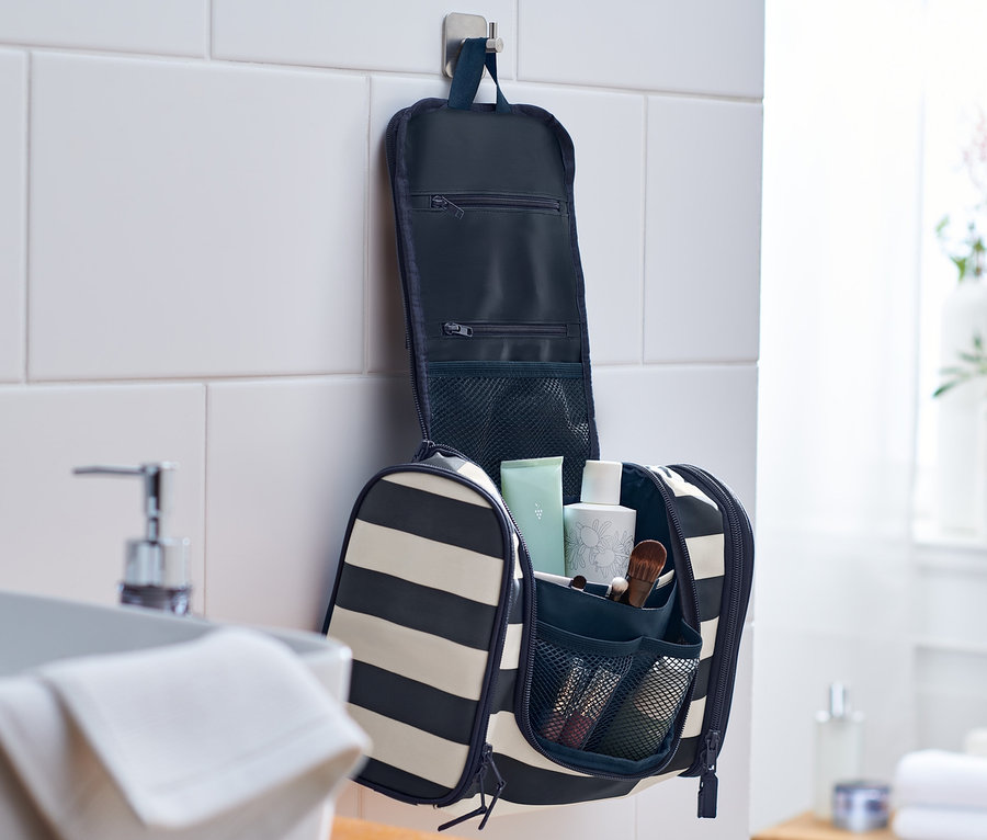 Pruhovaná toaletní taštička visí otevřená na zdi v koupelně.