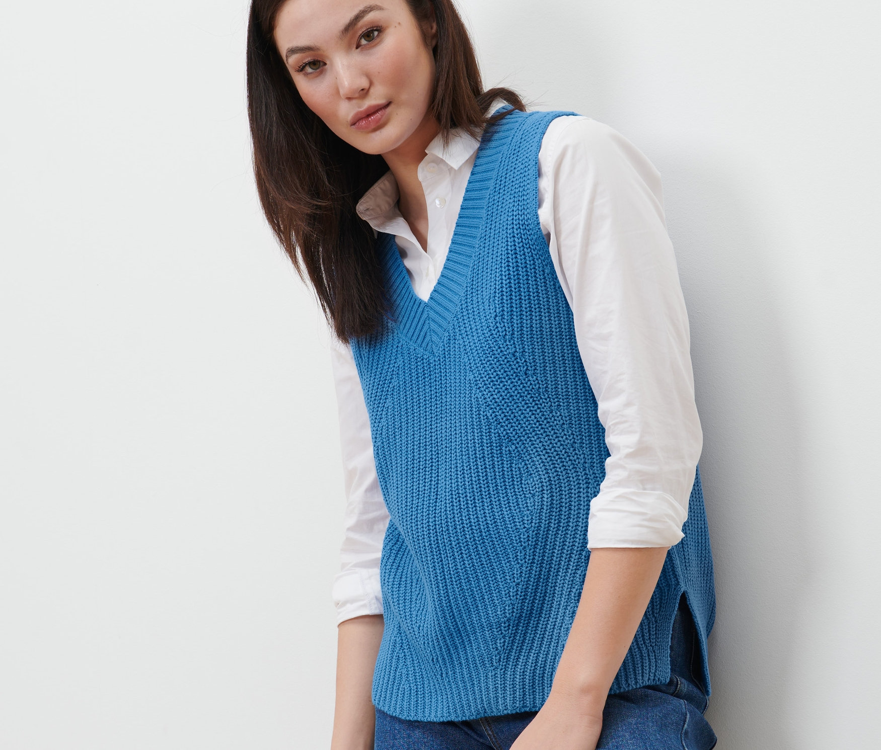 Žena má na sobě modrou pletenou vestu.