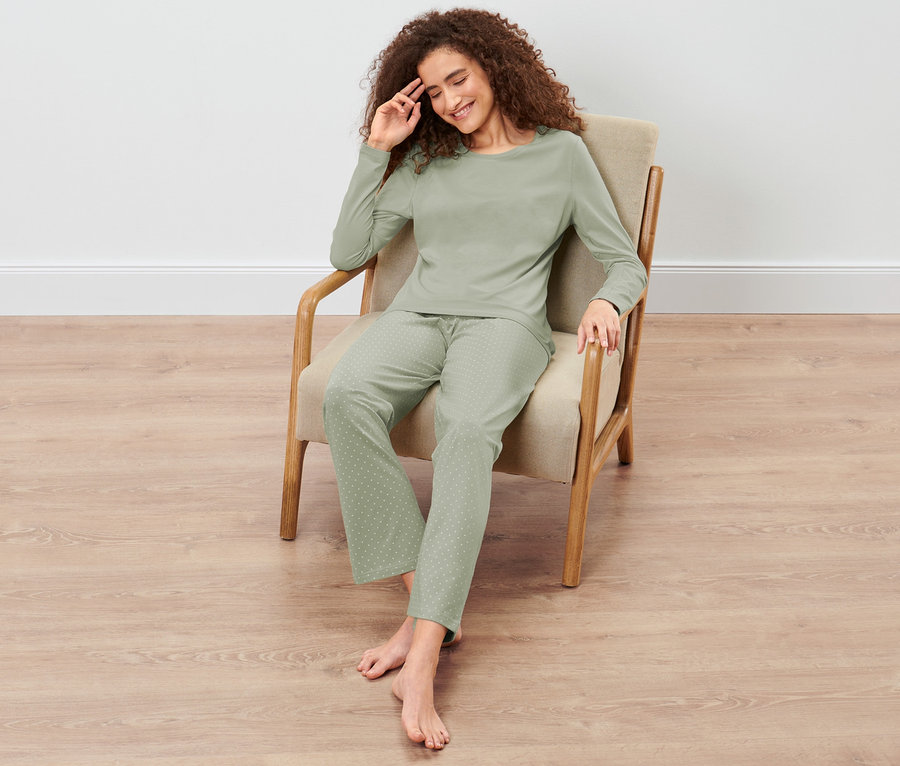 Žena sedí v křesle a má na sobě pyžamo.