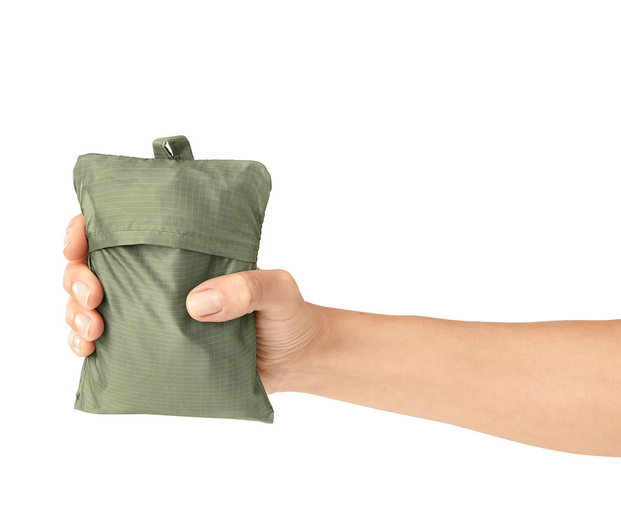 Ruka drží zelenou mini deku na piknik v obalu.