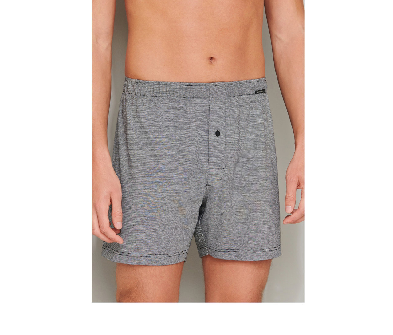 Muž v šedých bavlněných boxerkách SCHIESSER s elastickým pasem a zapínáním na knoflík.