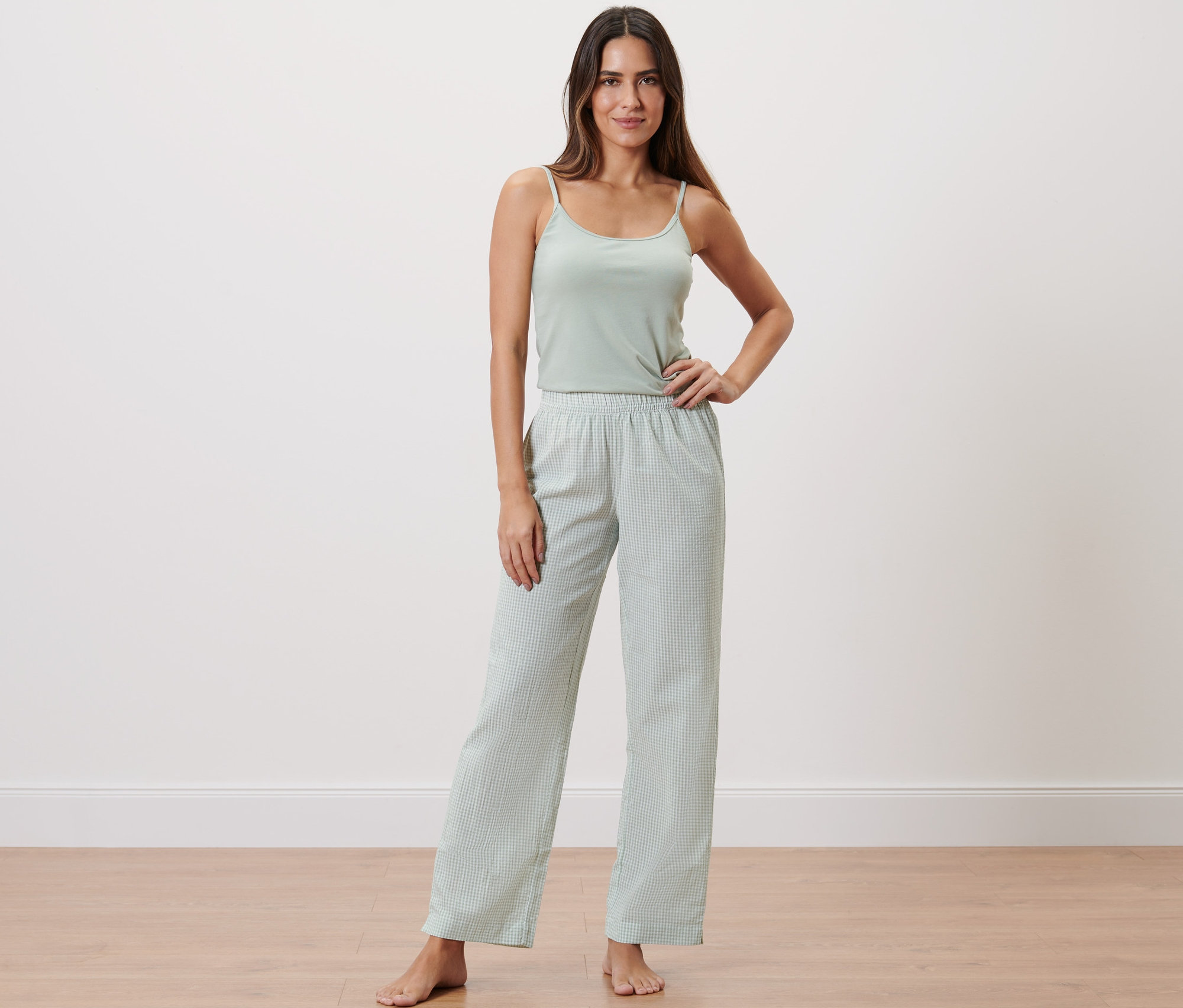 Žena stojí a pózuje v tkaných kalhotách.