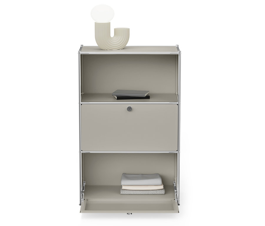 Šedá skříň se stříbrným rámem má otevřenou spodní polici se složeným oblečením a horní polici s knihami.