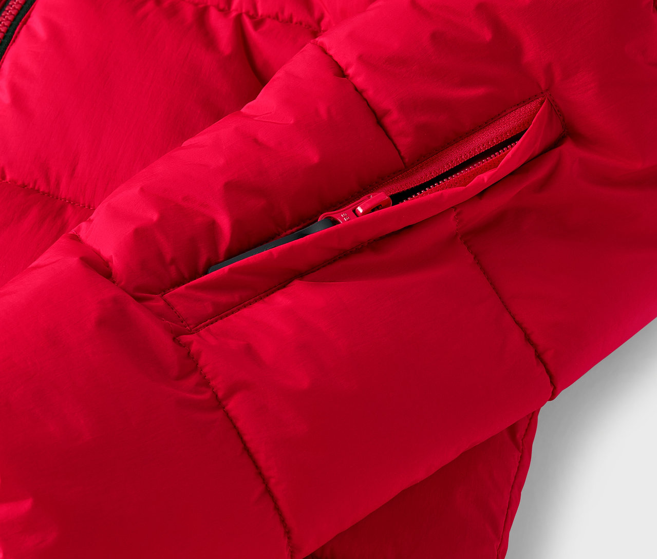 Detail červené prošívané bundy s kapsou na zip.